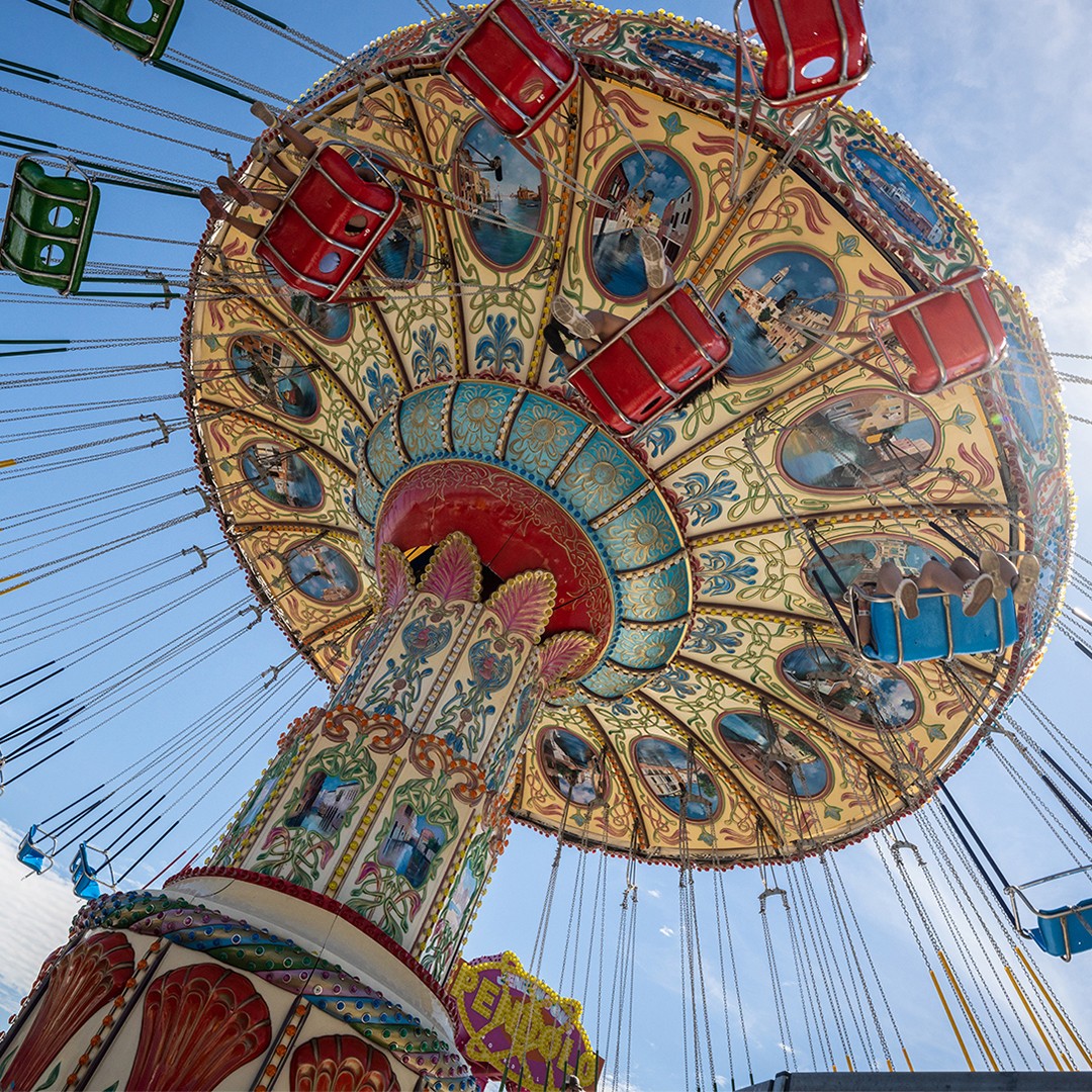 Children riding the swing ride at Jenkinson’s Boardwalk Amusement Park under a bright blue sky.