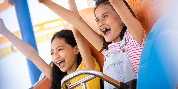 Action shot of girls riding roller coaster in the ride park on Jenkinson's boardwalk